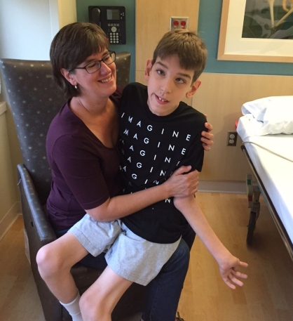 Justin sitting on Mom's lap in chair next to hospital bed