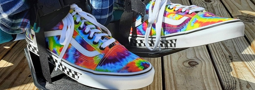 Tie-dye Vans shoes strapped on wheelchair footplates