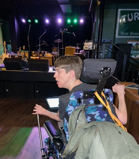 Justin in a power wheelchair in front of Turf Club stage before the show