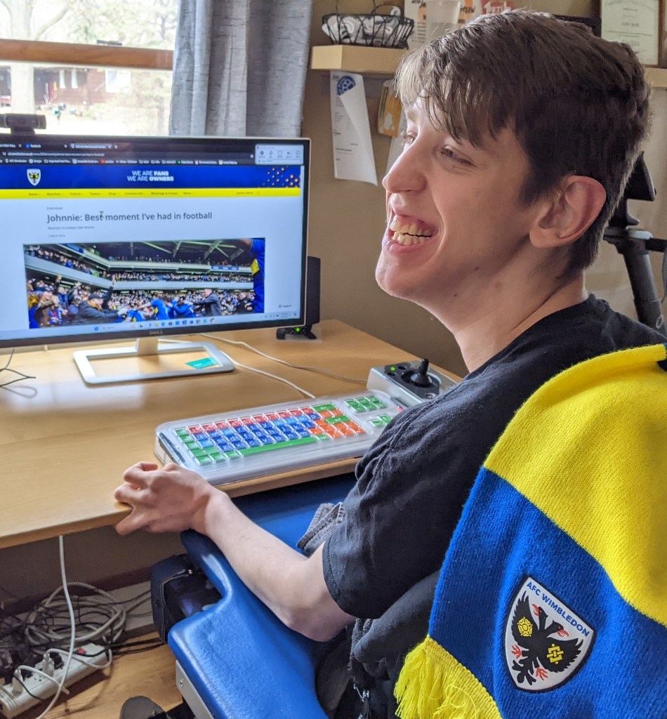 Justin smiling and looking to the side, Wimbledon post about their win on the computer monitor